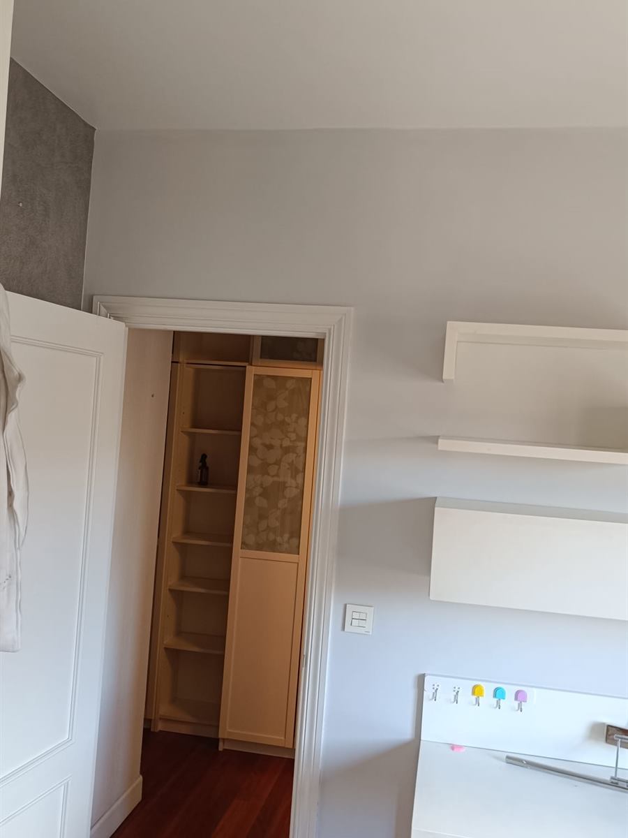 Dormitorio en blanco con una pared gris y estanterías