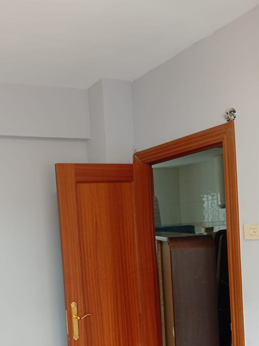 Después: la misma puerta con la pared reparada y pintada en gris claro